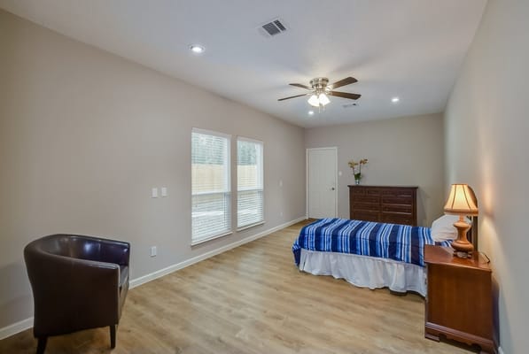 Bright and spacious bedroom with a bed, dresser, and seating area.