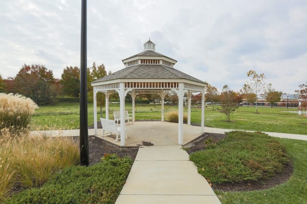A white gazebo surrounded by greenery at a senior living facility