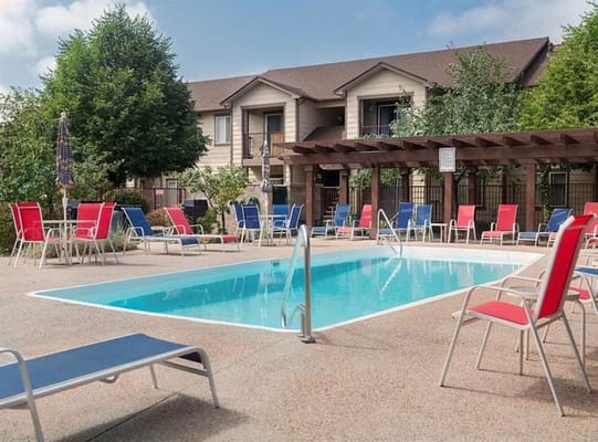 Outdoor pool surrounded by lounge chairs at Reflections senior living facility.