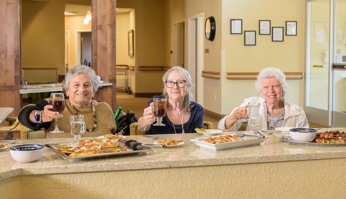 Three residents toasting with drinks in a dining setting