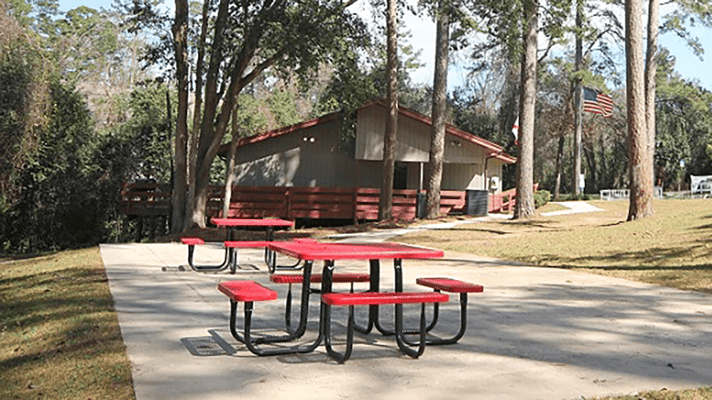 Outdoor picnic area with red tables near a building