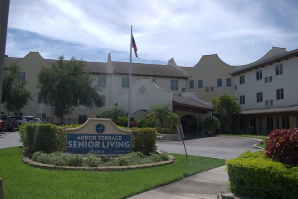 Entrance sign of Arbor Terrace Citrus Park with American flag
