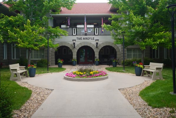 Welcoming entrance with flower beds and seating area at The Argyle