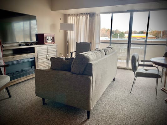 A comfortable living room with a couch, TV, and balcony access