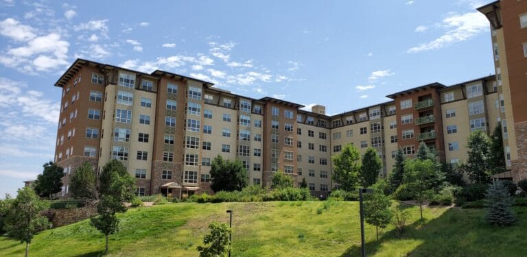 Exterior of Wind Crest Senior Living Community showing a multi-story building and surrounding landscape.