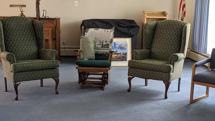 Two green armchairs and a rocking chair in a living room setting.