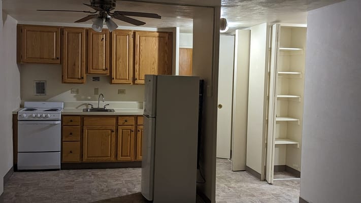 Small kitchen with wooden cabinets and white appliances