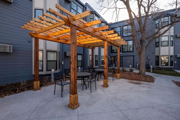 Wooden pergola with tables and chairs in an outdoor setting