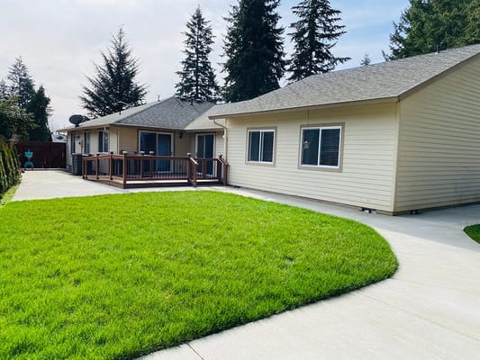 Single-story adult family home with green lawn and deck