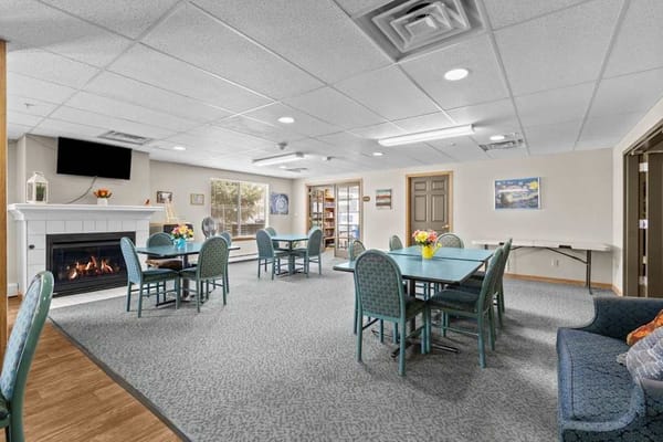 A spacious common area with tables and chairs, a fireplace, and a cozy atmosphere.