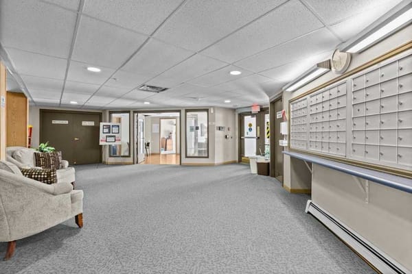 A spacious hallway with mailboxes and seating area in Town Centre Senior Apartments.