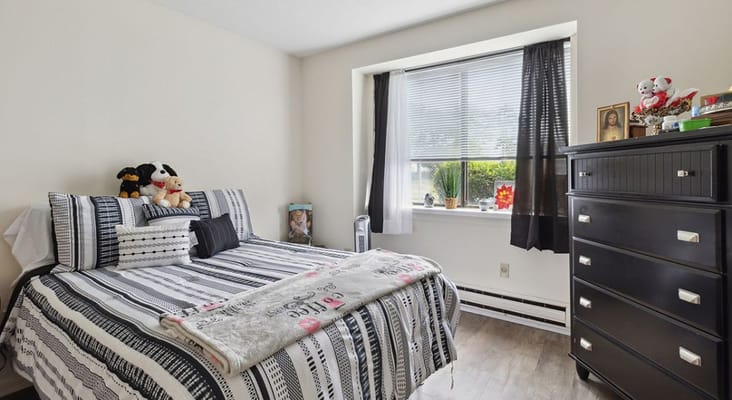A comfortable bedroom with a bed, stuffed animals, and a dresser.