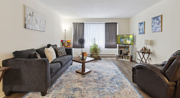 Living room with a sofa, coffee table, and TV in a senior apartment.