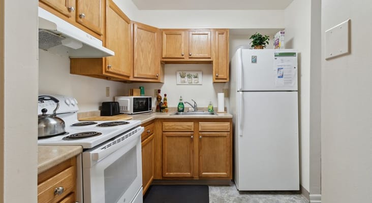 View of a kitchen with wooden cabinets and white appliances