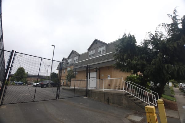 Front view of Life Manor Independent Living building with a fenced parking area
