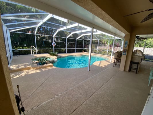 Inviting pool area enclosed with screen, featuring seating and tropical plants