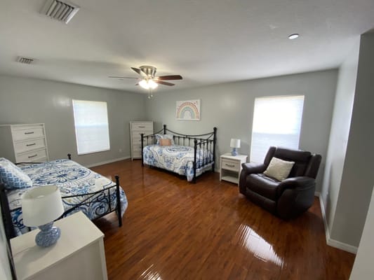Bright and spacious shared bedroom with two beds and a recliner