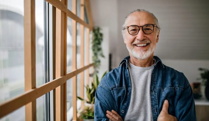 Smiling elderly man standing by a window