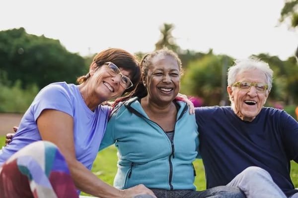 Three residents smiling together in a garden setting