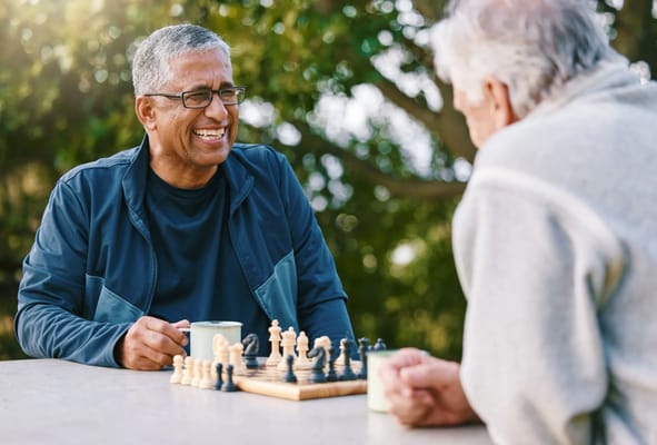 Two men playing chess outdoors with coffee