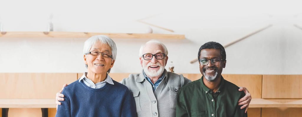 Three smiling seniors posing together in a common area