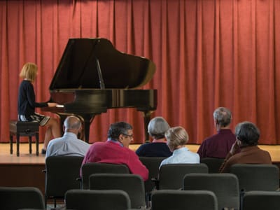 Residents enjoying a live piano performance in the activity room