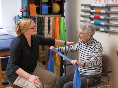 Therapist assisting a resident with exercise bands