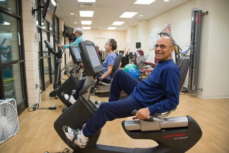 Residents using fitness equipment in an exercise room