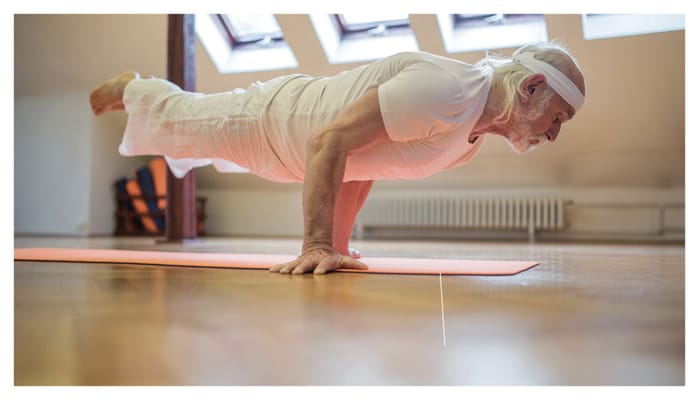 An elderly man practicing yoga on a mat in a bright room
