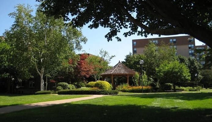 A gazebo surrounded by lush greenery and colorful flowers at Shepherd Park Elderly Housing.
