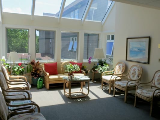 A sunroom with comfortable seating and plants.