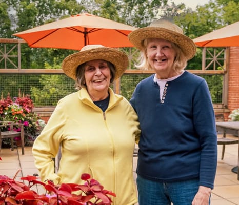 Two smiling residents in a garden patio