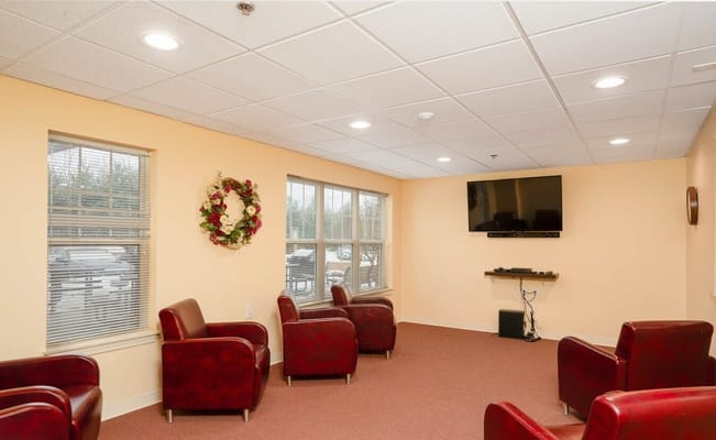 Lounge area with red chairs, TV, and a decorative wreath