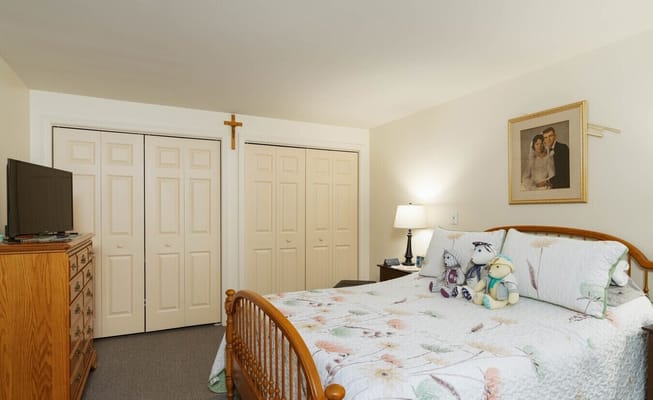A well-decorated bedroom with a wooden bed, dresser, TV, and artwork.