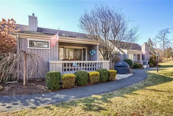 View of the front entrance of Oronoque Village with seating area and landscaping.