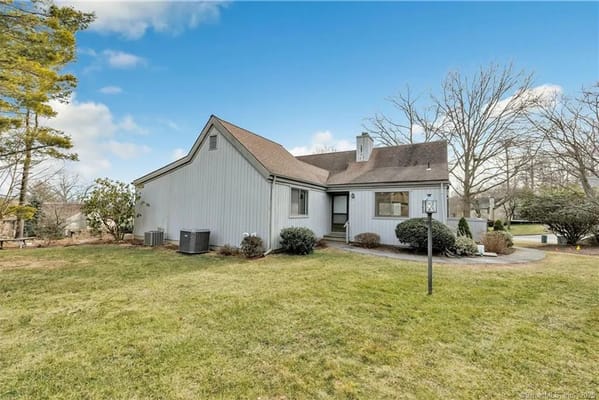 Single-story building with a sloped roof and landscaped yard at Oronoque Village