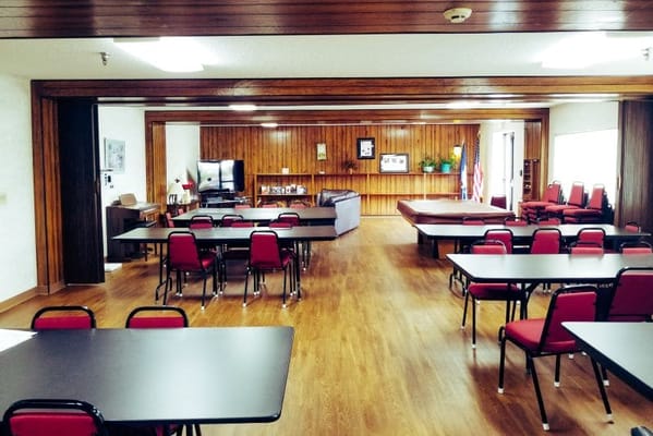 Spacious common room with tables and red chairs in Willow Arms Apartments