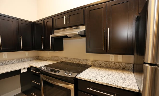 A modern kitchen featuring dark cabinetry and granite countertops.