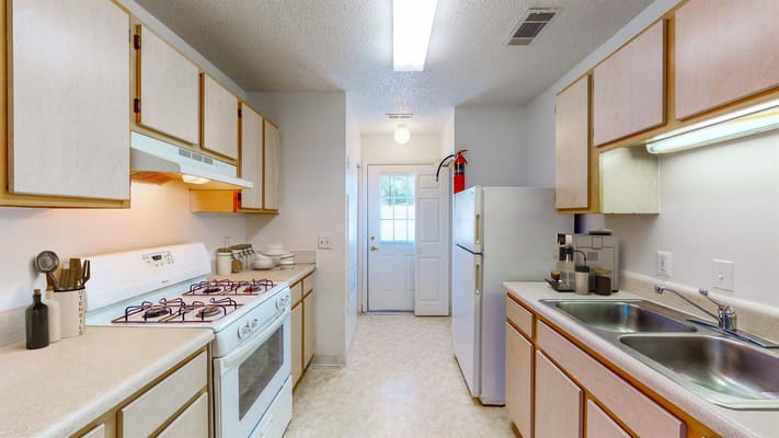 Bright kitchen featuring stove, sink, and refrigerator.
