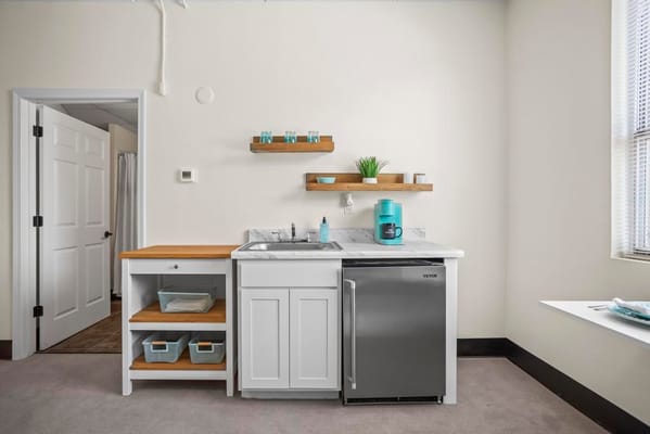 Bright kitchenette with sink, fridge, and shelving