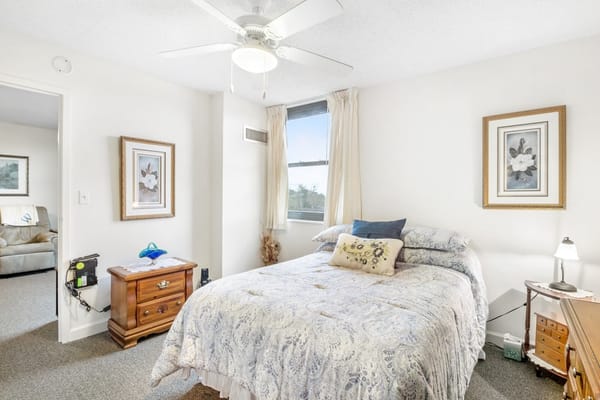 A well-decorated bedroom featuring a bed, nightstand, and window with curtains.