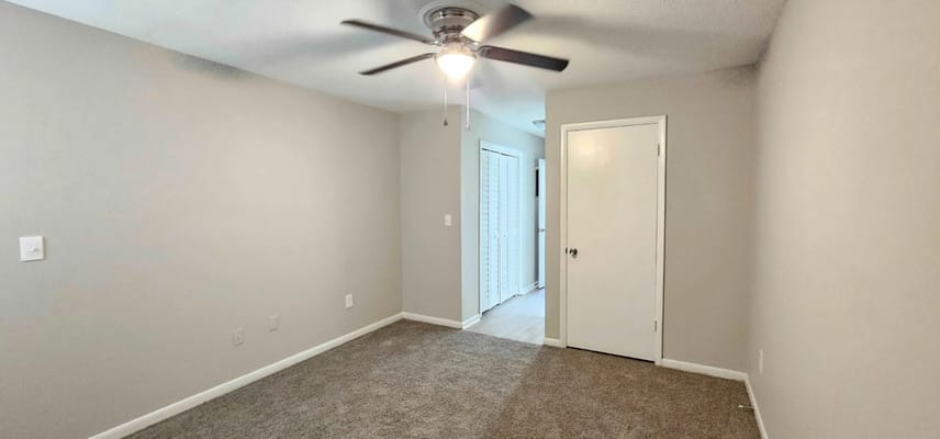 Empty resident room with carpet and ceiling fan