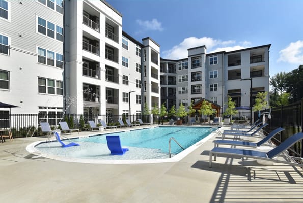 Pool area with lounge chairs and surrounding apartments