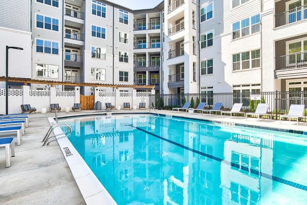 Swimming pool area with lounge chairs and building in background
