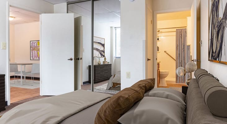 View of a bedroom leading to an adjoining bathroom and dining area.