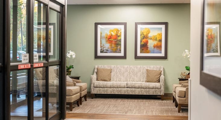 Inviting lobby area with a sofa and armchairs, featuring artwork on the walls.