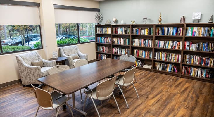 A library space with bookshelves, a table, and comfortable seating.