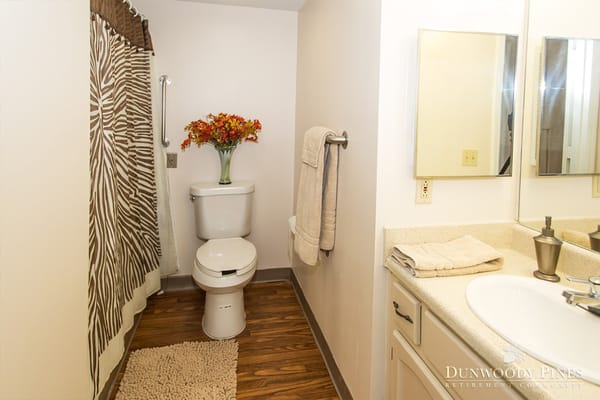Spacious bathroom featuring a toilet, sink, and decorative flowers.