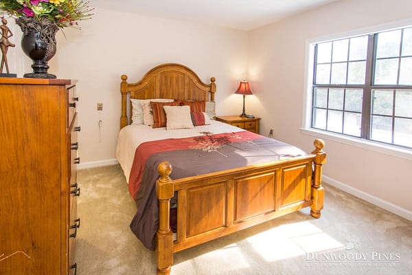 A well-furnished bedroom with wooden furniture and decorative pillows.