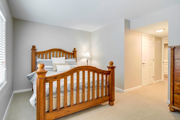 Cozy bedroom featuring a wooden bed frame and soft lighting.